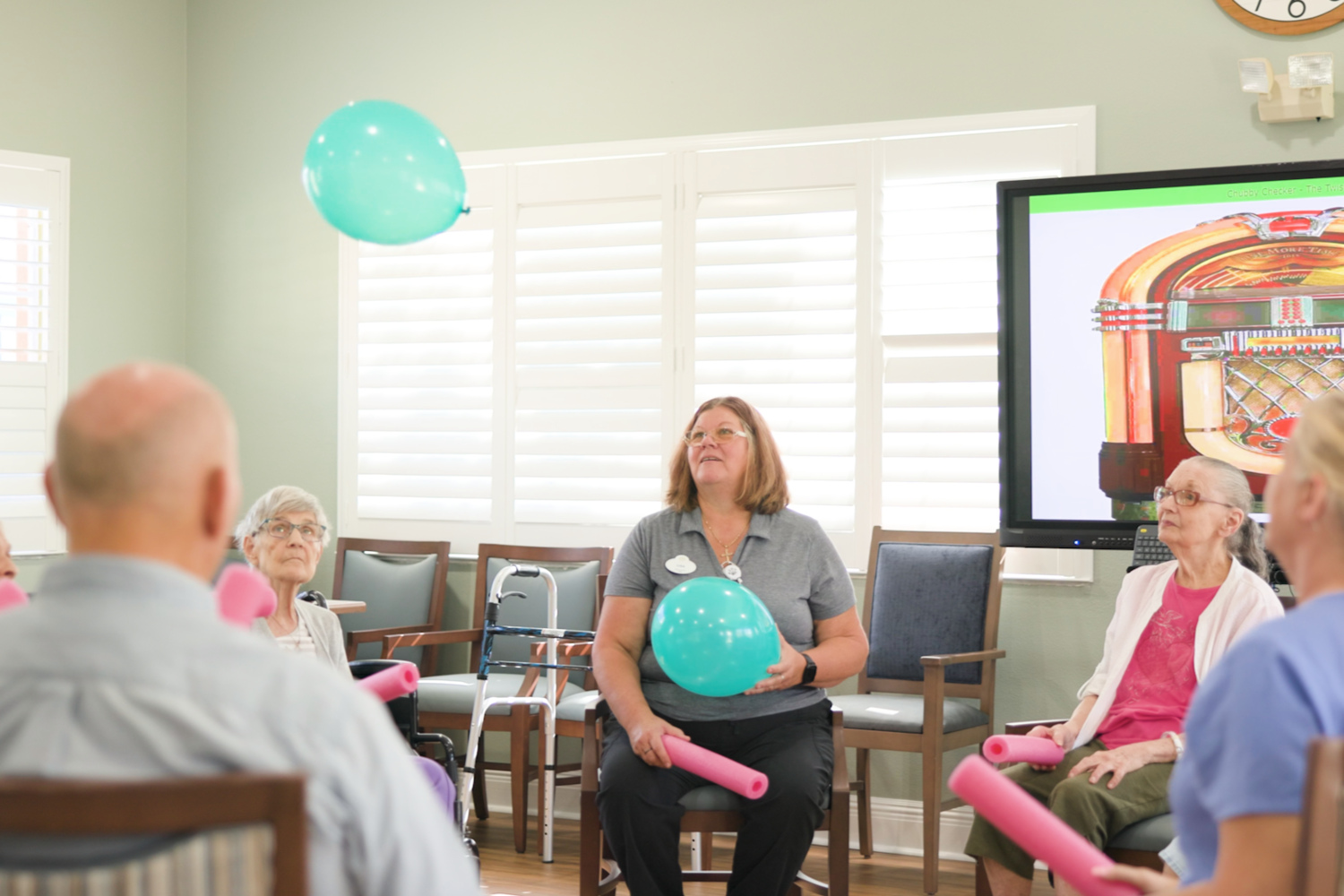 Residents and staff participate in a lively group activity in a bright common room at Barrington Terrace senior living in Fort Myers, FL.
