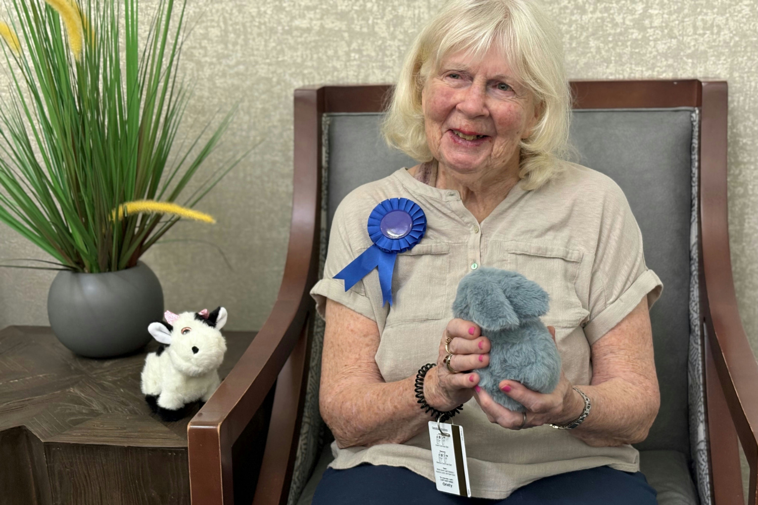 A smiling resident holds a stuffed animal and a blue ribbon prize at a cheerful community event at Barrington Terrace of Fort Myers, FL.