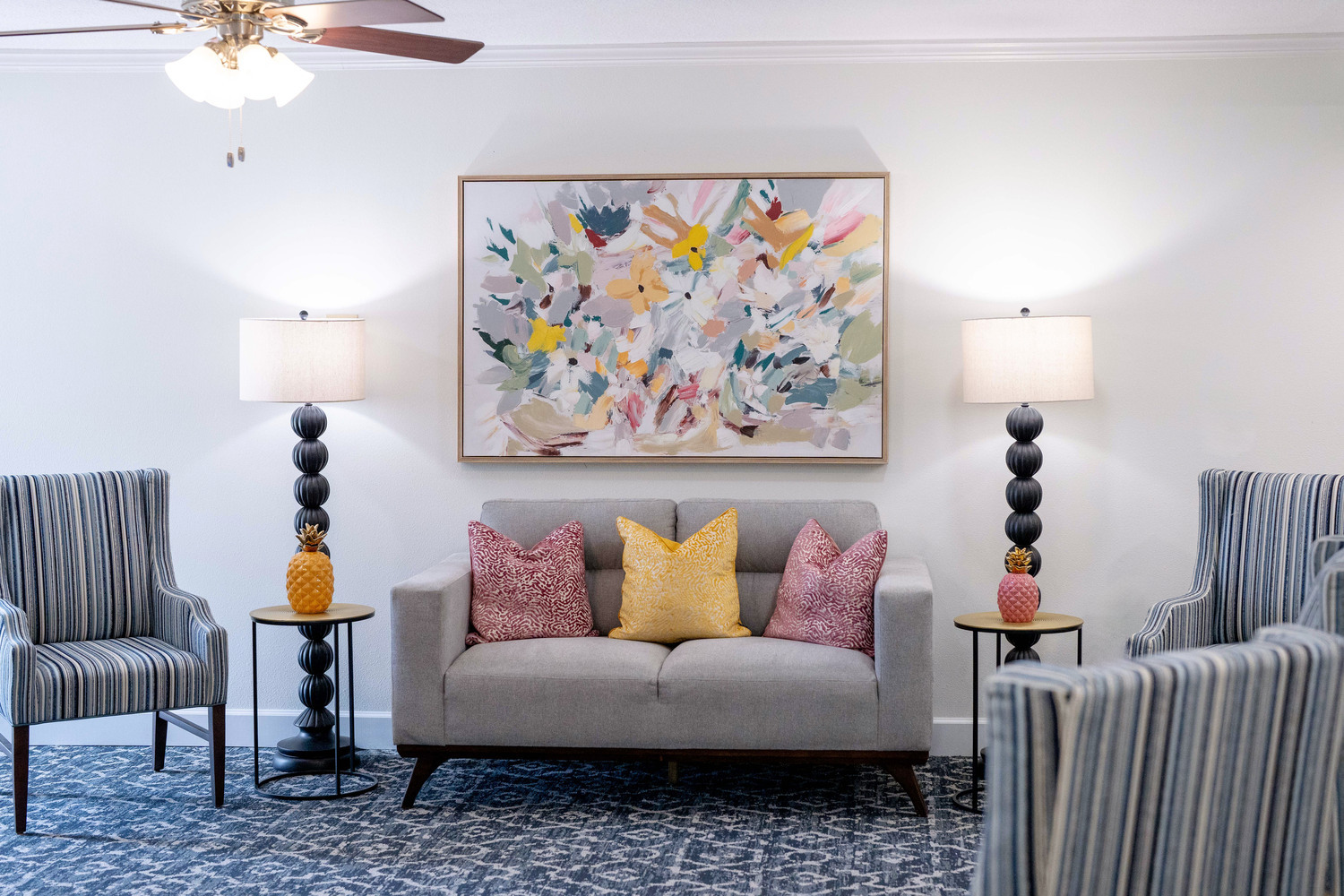 Thoughtfully decorated apartment living room with striped armchairs, colorful artwork, and warm accent lighting at this senior living community in Fort Myers, FL.