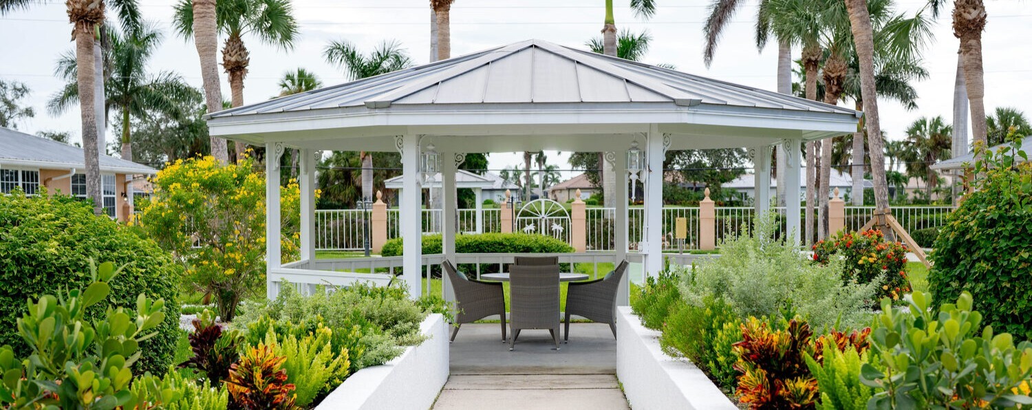 Charming gazebo surrounded by vibrant tropical landscaping and palm trees at this senior living community in Fort Myers, FL, perfect for enjoying the outdoors.