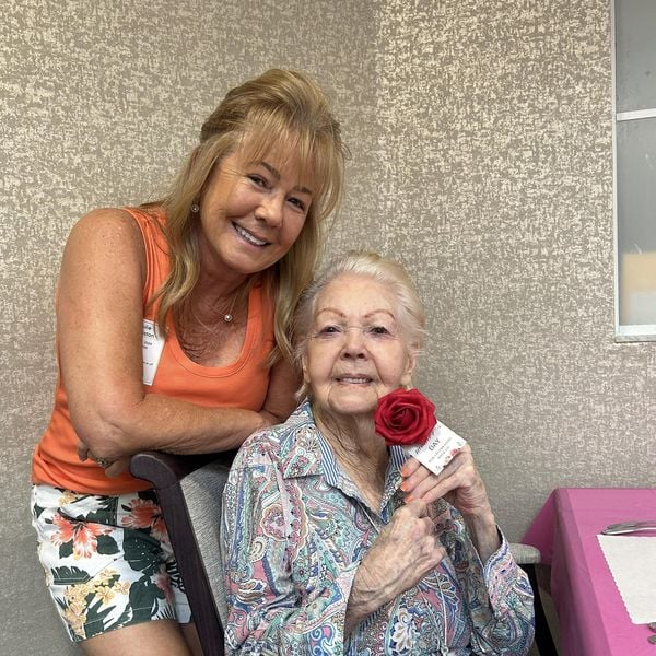 A resident holds a red rose while posing warmly with a companion at Barrington Terrace senior living in Fort Myers, FL.