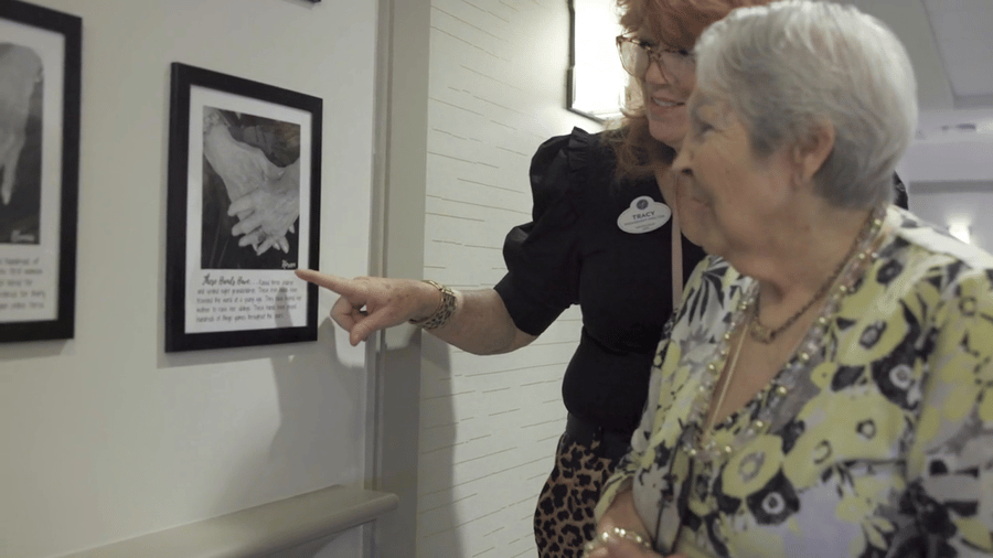 a senior lady and a staff member discussing a framed photo