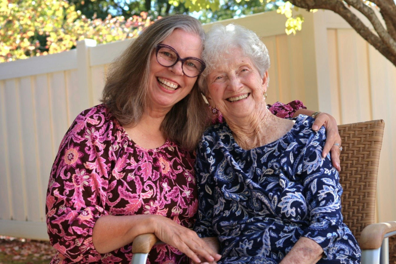 2 ladies smiling with arms around each other