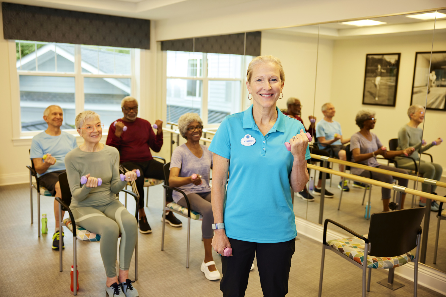 Staff members and residents in a fitness class doing chair weights