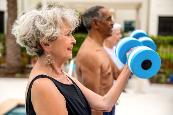 Seniors exercise outdoors with hand weights, smiling and staying active, reflecting the health and wellness programs that support cognitive care and an engaging senior lifestyle in Acworth, GA.