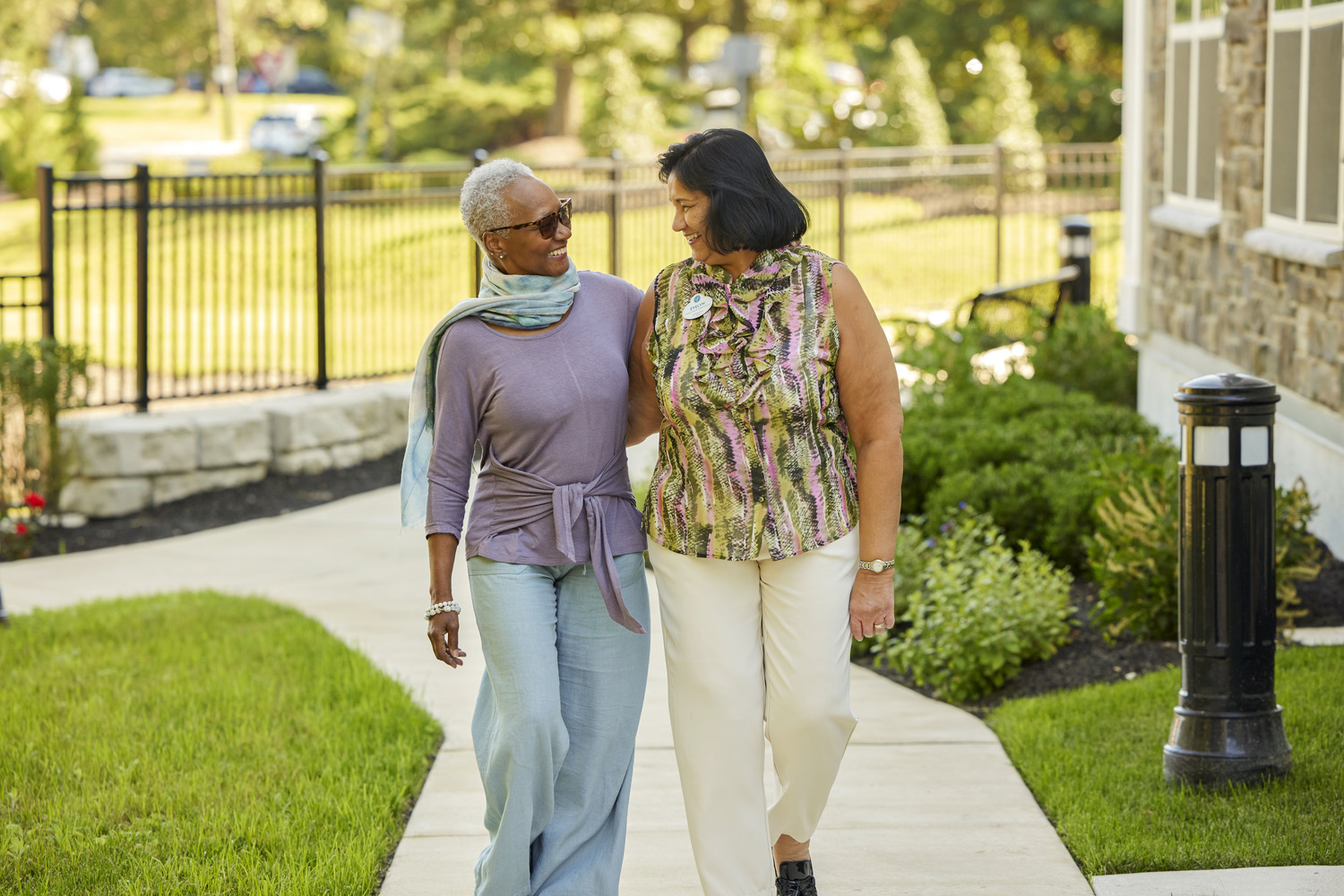 Resident and staff member walking outside on sidewalk