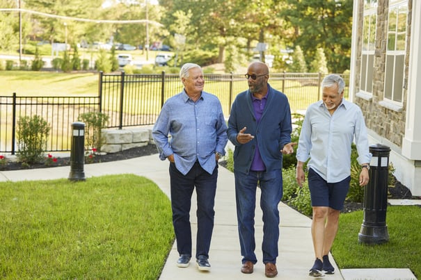 Three residents walk together along a landscaped outdoor path, enjoying conversation and fresh air, reflecting the walkable senior living and active lifestyle near Acworth, GA.