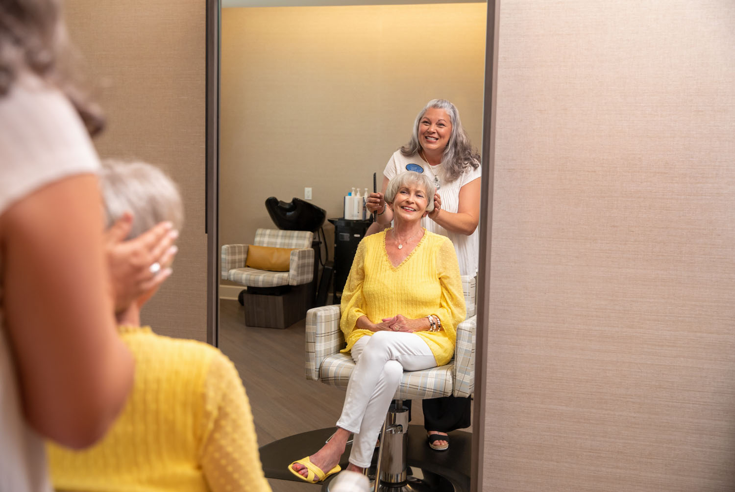Staff member doing seniors hair in front of mirror