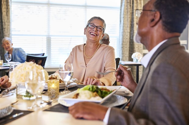 Residents enjoy lively conversation over a chef-prepared meal at an elegantly set table, showcasing the chef-prepared dining senior living in Sandy Springs, GA and Dunwoody, GA.