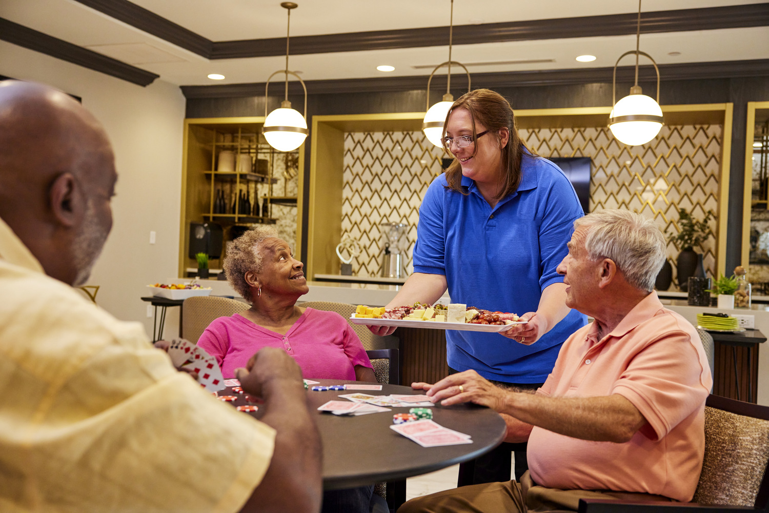 Staff members playing cards while a staff member serves them