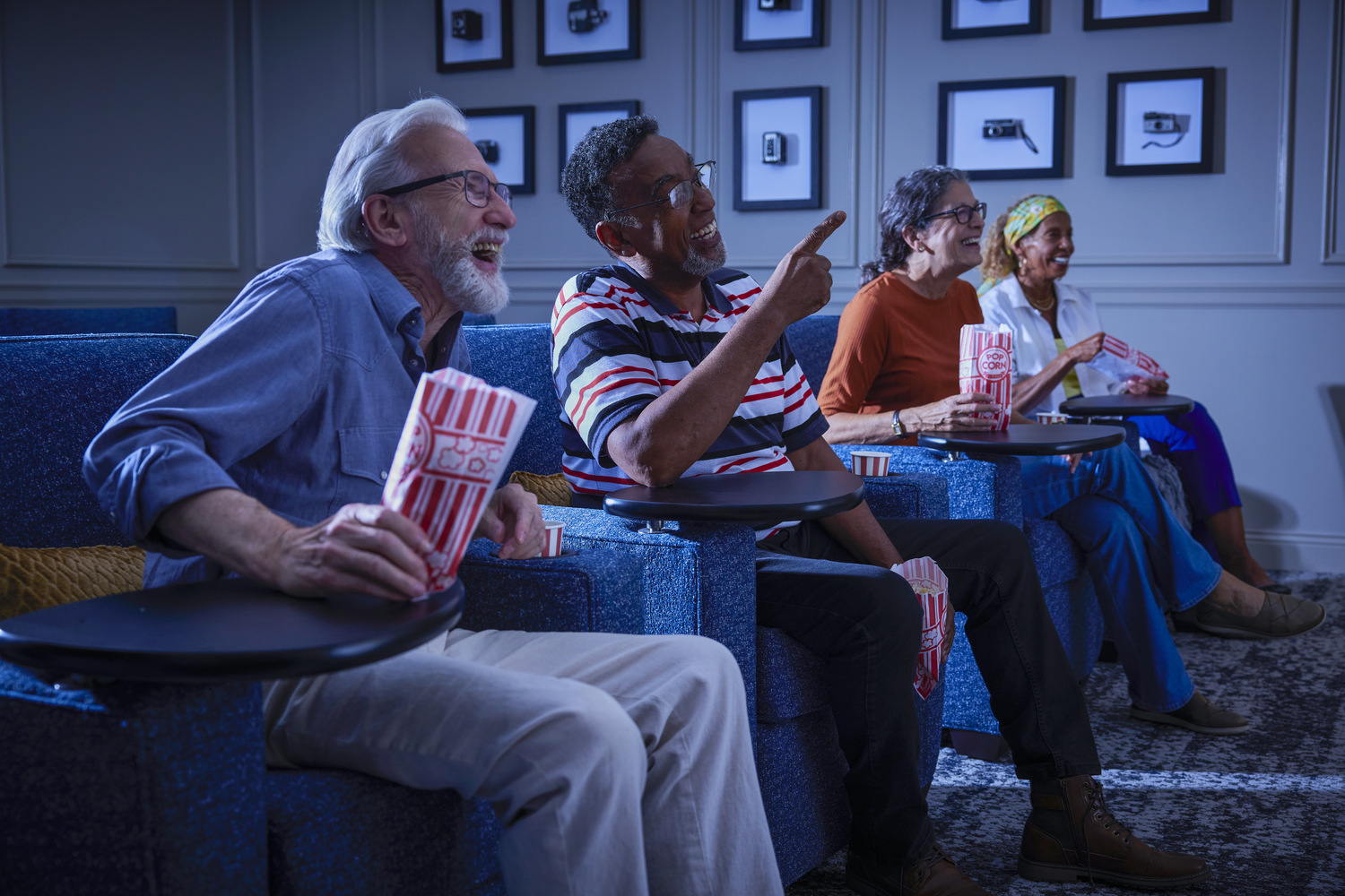 Seniors watching a movie in blue chairs eating popcorn