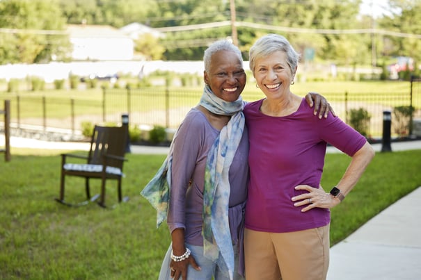 two senior ladies smiling and hugging
