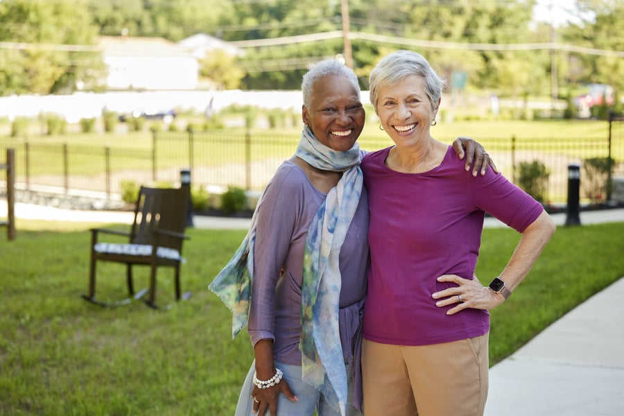 two senior friends side hugging