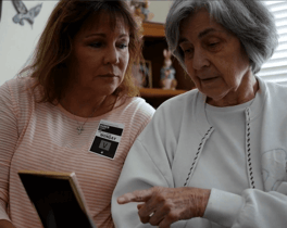 A staff member and resident share a meaningful moment looking at a framed photo together at this assisted living community in Shrewsbury NJ, reflecting the warm, person-centered care that defines senior living in Monmouth County