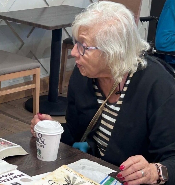 A community member enjoys a coffee at a cafe table at this Glenview senior living community, part of the senior care Glenview Illinois this community provides.