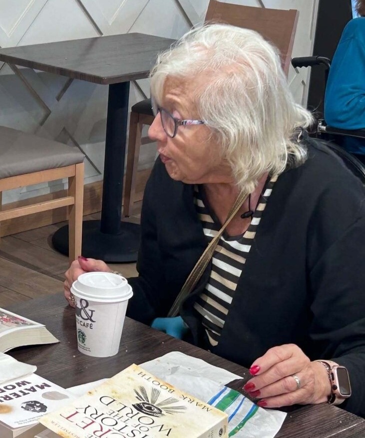 A community member enjoys a coffee at a cafe table at this Glenview senior living community, part of the senior care Glenview Illinois this community provides.