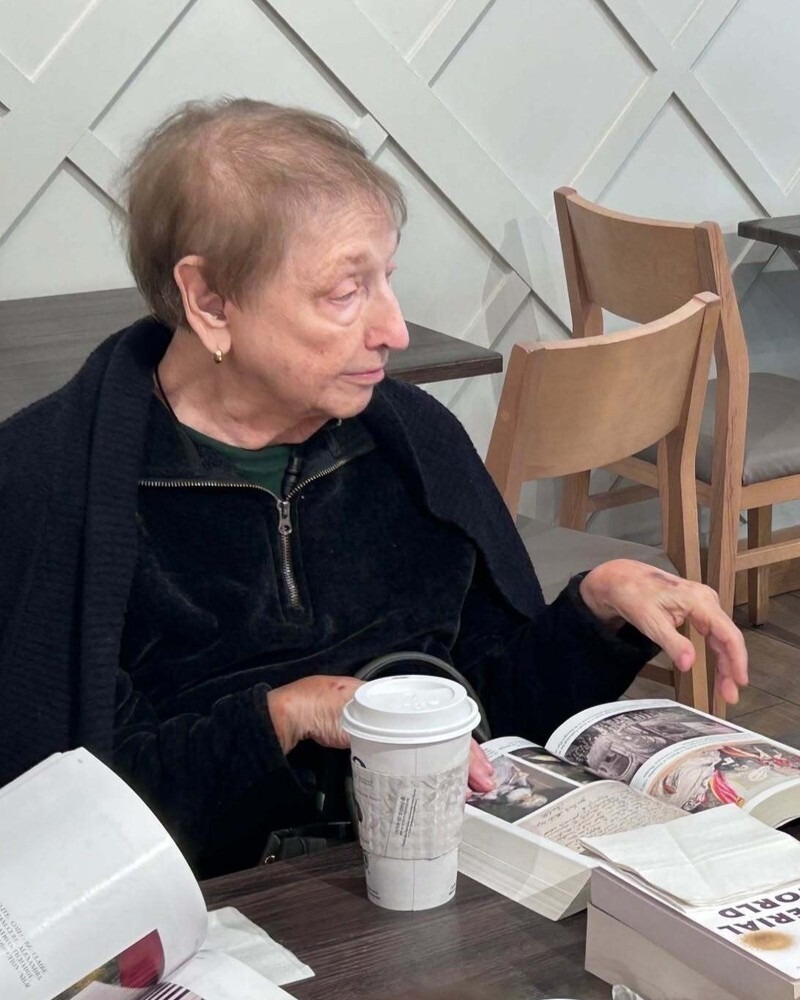 A community member enjoys a coffee and browses a book at a cafe table at this Glenview senior living community, part of the senior care Glenview Illinois this community provides.