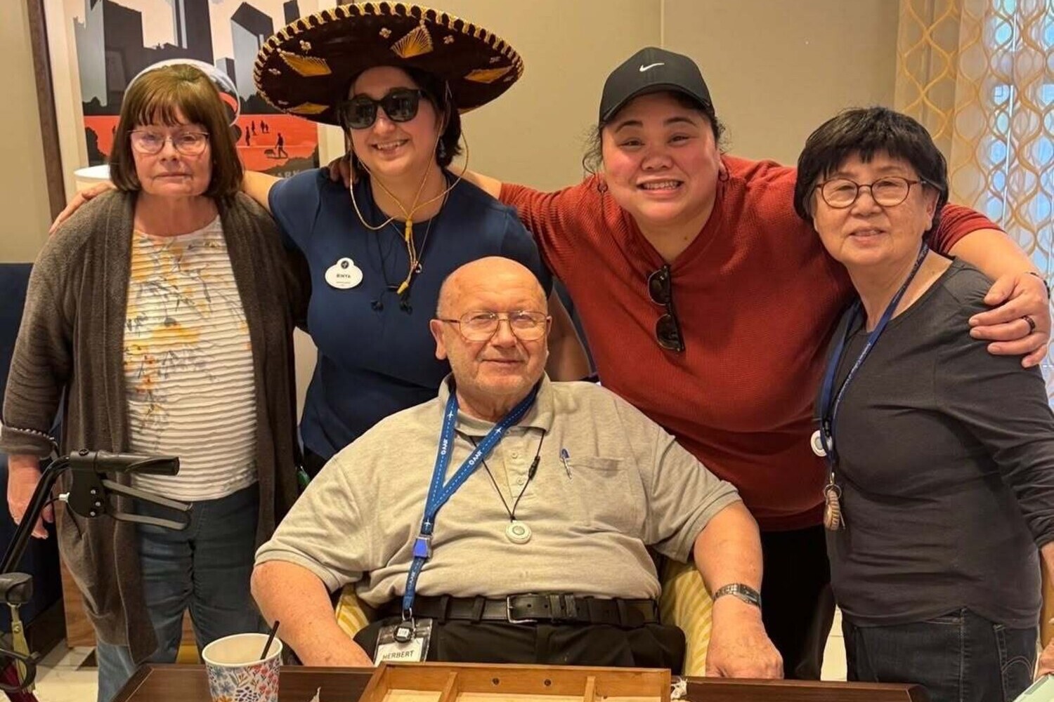 A group of community members gather and smile together at this Glenview senior living community, one wearing a festive sombrero, capturing the warmth of senior living near The Glen Town Center.