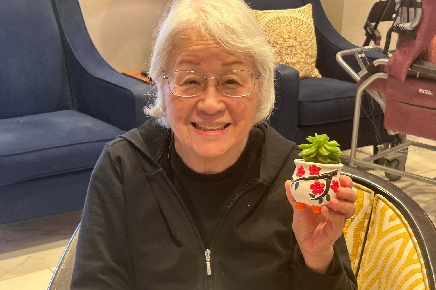 A community member proudly displays a hand-painted planter during a craft activity, showcasing the resort-style charm found at this Glenview senior living community.
