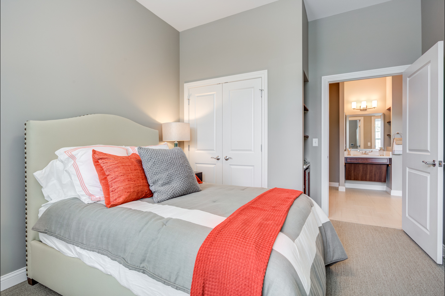 The bedroom at Arbor Terrace Glenview senior living offers a cozy bed with a bold accent throw and an adjoining private bathroom, reflecting assisted living in Glenview Illinois.