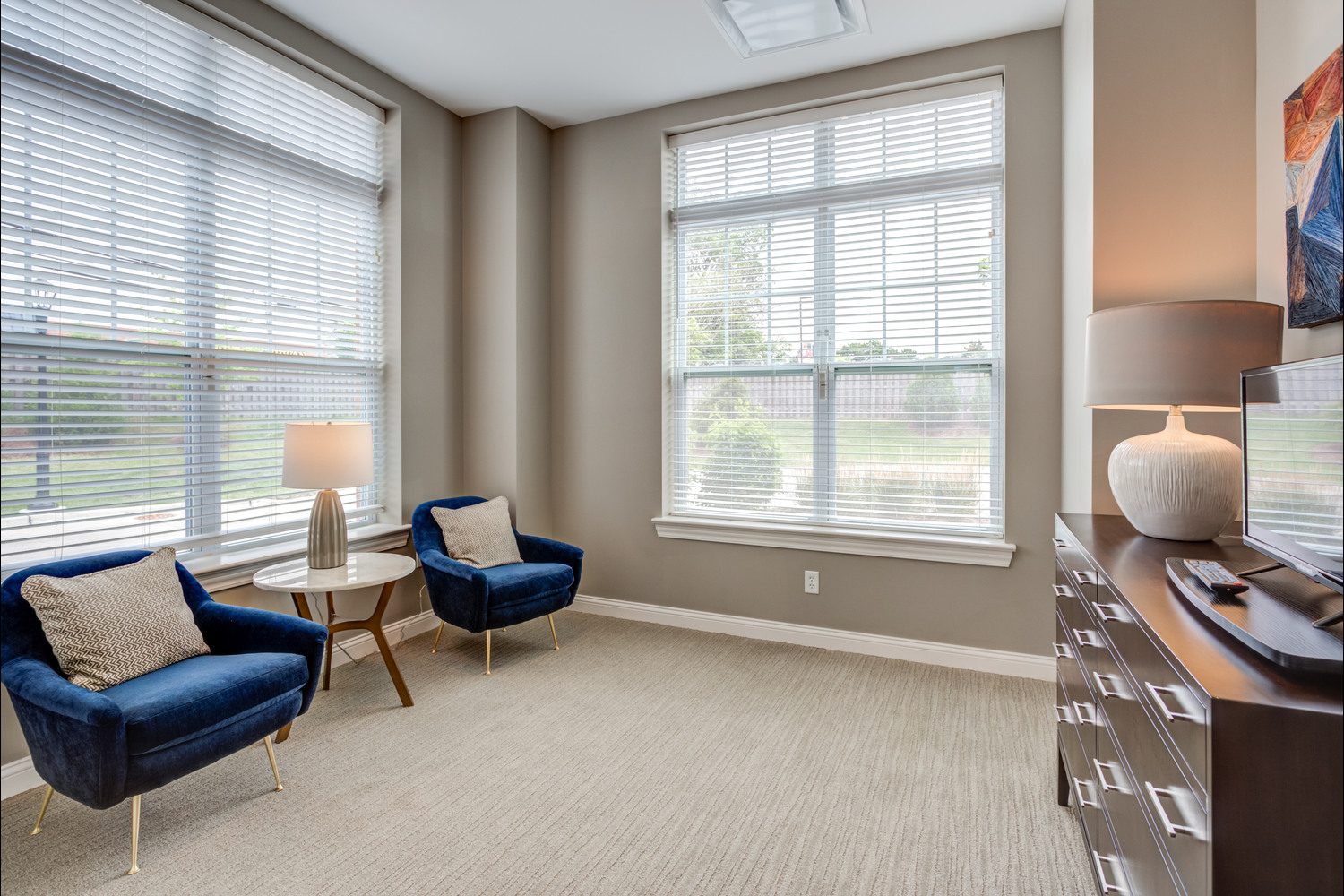 The bedroom sitting area at Arbor Terrace Glenview senior living features comfortable lounge chairs and large windows, part of the assisted living in Glenview Illinois lifestyle.