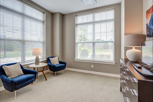 The bedroom sitting area at Arbor Terrace Glenview senior living features comfortable lounge chairs and large windows, part of the assisted living in Glenview Illinois lifestyle.