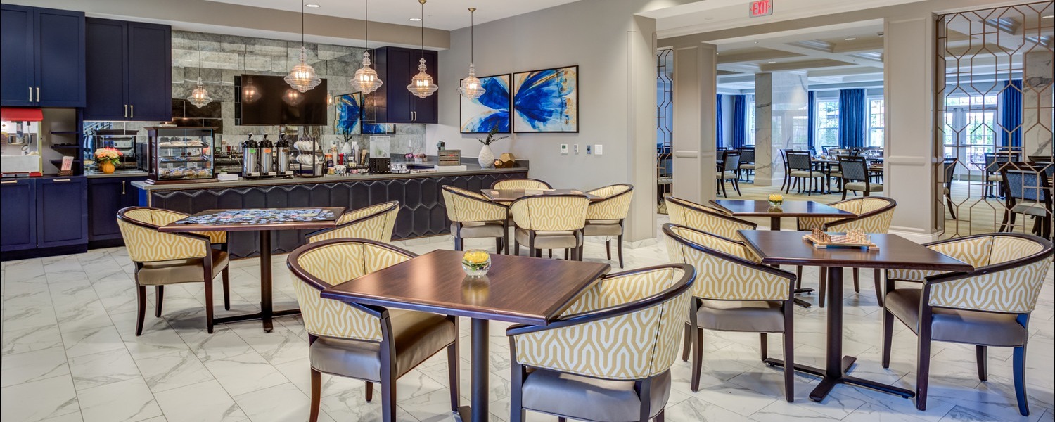 An elegant dining and cafe area with a marble buffet counter, pendant lighting, and patterned dining chairs at this boutique senior living Greenville community, part of the senior living with gourmet dining Greenville offers.