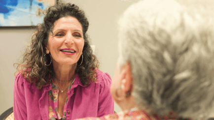 A woman shares a warm, attentive conversation with an older adult, reflecting the caring guidance and personal attention found at this Glenview senior living community.
