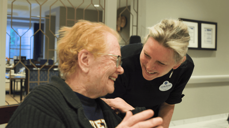 A smiling resident shares a joyful moment with a caring staff member, capturing the warmth of senior living in Glenview, IL at Arbor Terrace Glenview.