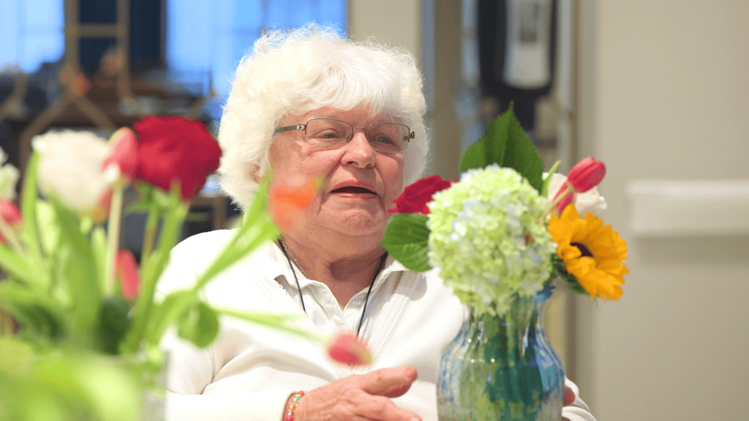A resident at Arbor Terrace Glenview senior living admires a colorful bouquet of fresh flowers, enjoying the active senior lifestyle Glenview provides.