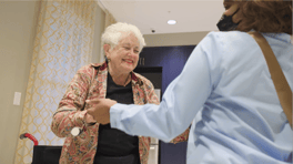 A resident and staff member share a warm handshake at Arbor Terrace Glenview senior living, reflecting the close bonds that come with the active senior lifestyle Glenview offers.