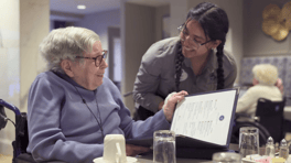 A resident and staff member share a warm smile while reviewing a menu together at Arbor Terrace Glenview senior living, reflecting the welcoming spirit of senior living in Glenview Illinois.