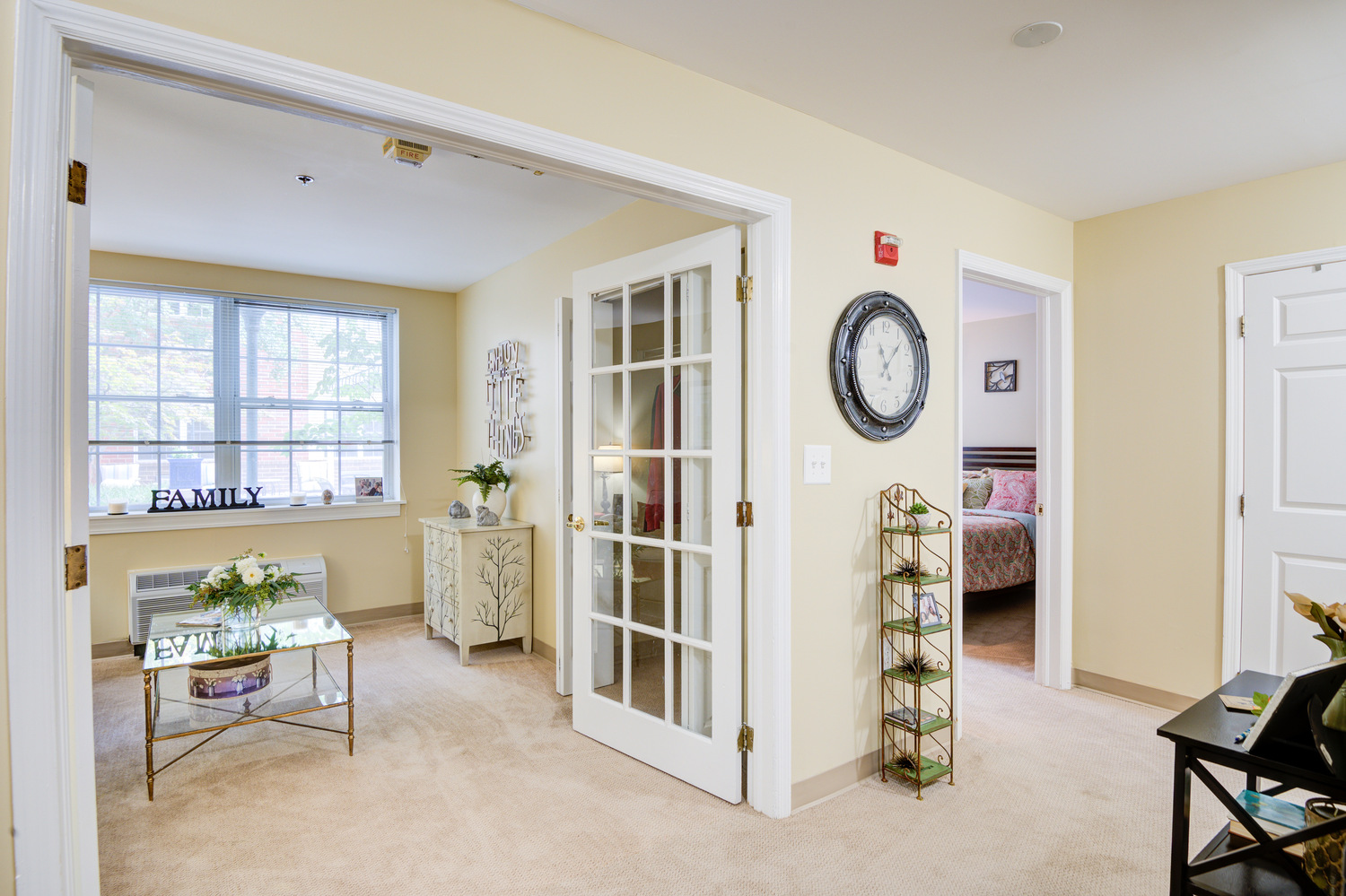 Sunlit apartment entryway with French doors, neutral tones, and an open layout at Arbor Terrace, offering comfortable assisted living in Lanham, MD near Greenbelt.