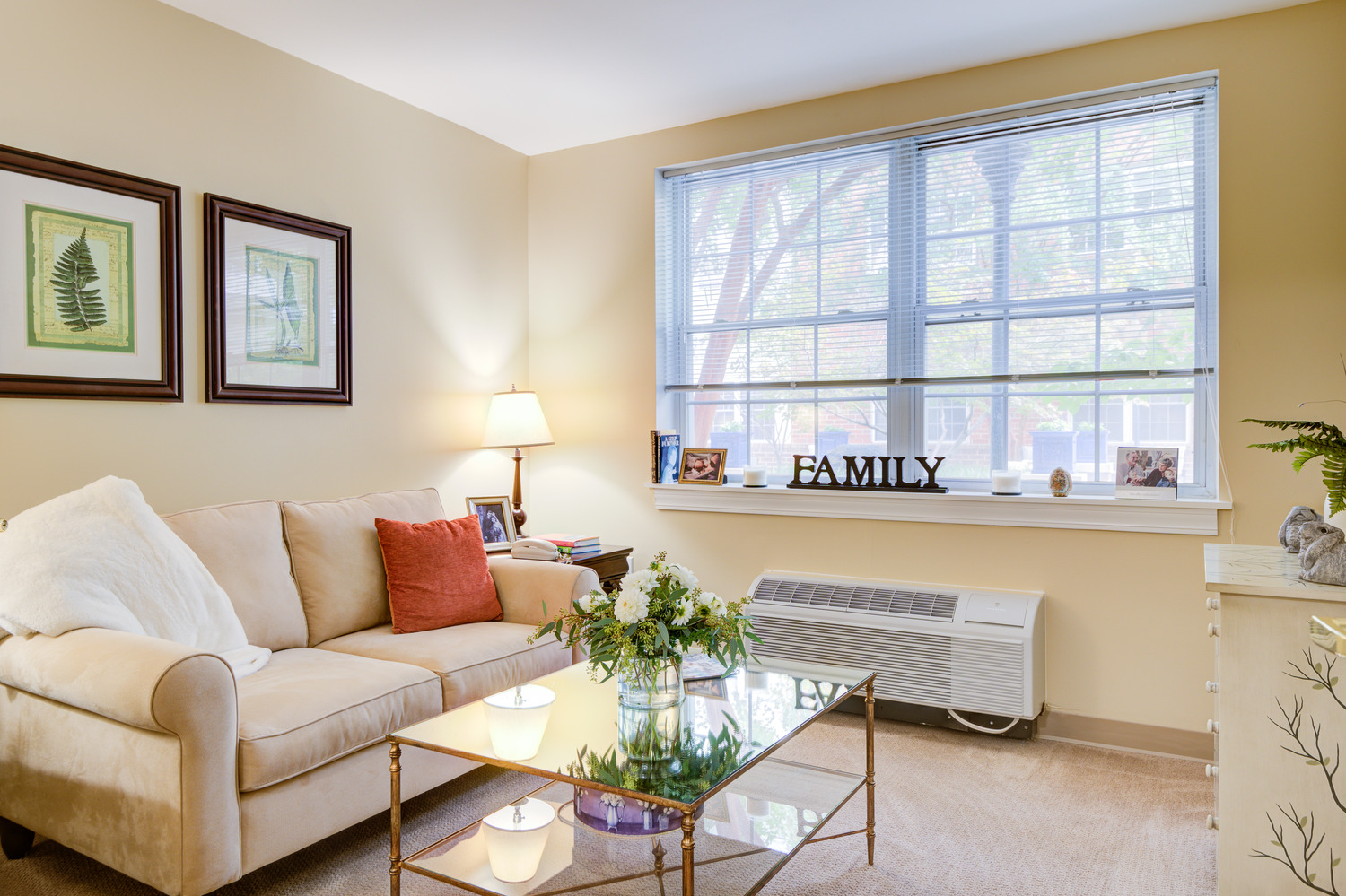 Cozy apartment living room with plush seating, warm lighting, and a "Family" wall décor at Arbor Terrace, a welcoming senior living community near Greenbelt, MD.