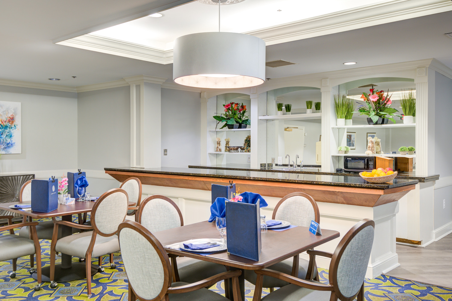 Inviting dining area with a built-in serving counter, open shelving, and fresh floral accents at Arbor Terrace, a senior living community with on-site dining in Lanham, MD.