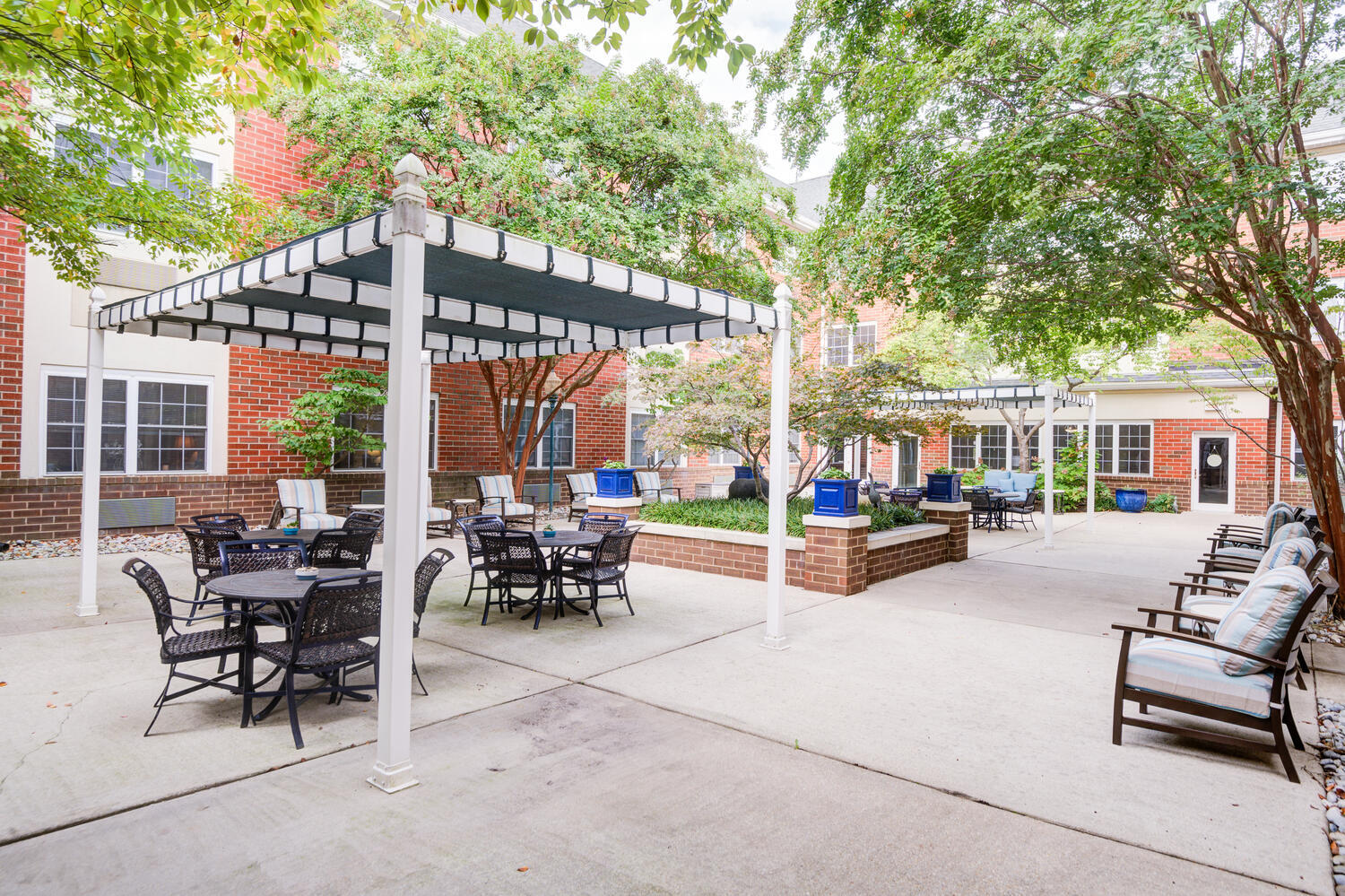 A beautifully landscaped courtyard with seating and pergola at Arbor Terrace Senior Living, offering residents active senior living near Greenbelt Park in Lanham, MD.
