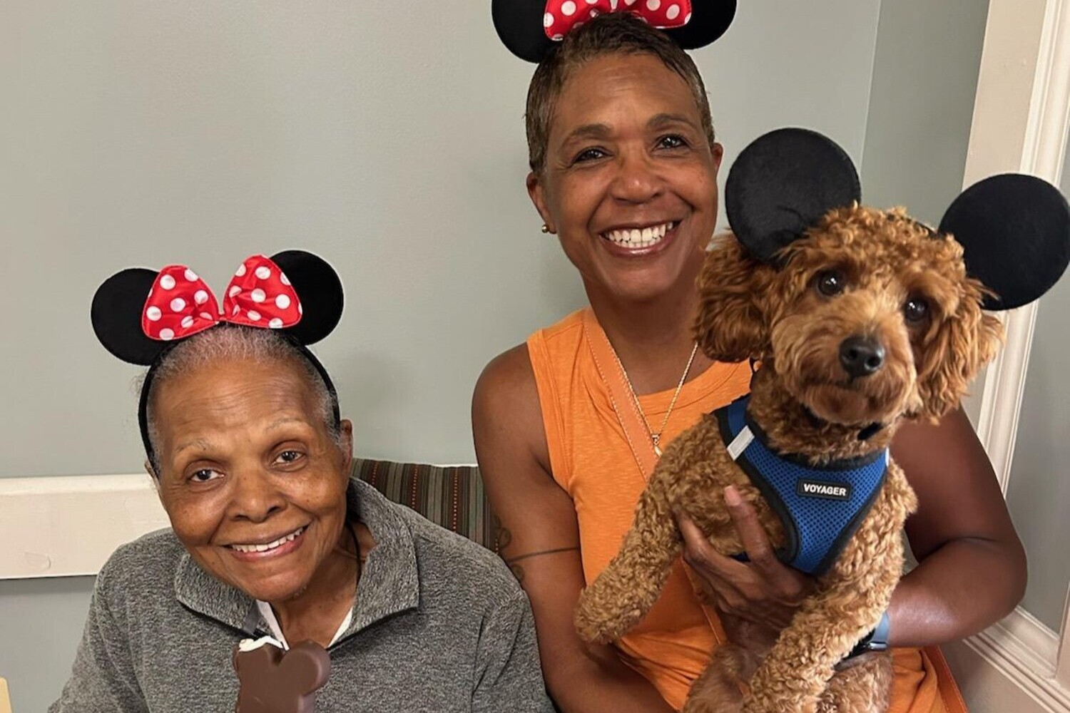 A smiling resident and staff member pose with an adorable therapy dog at this pet-friendly senior living community in Lanham, MD, where animal visits bring joy and comfort to everyday life.