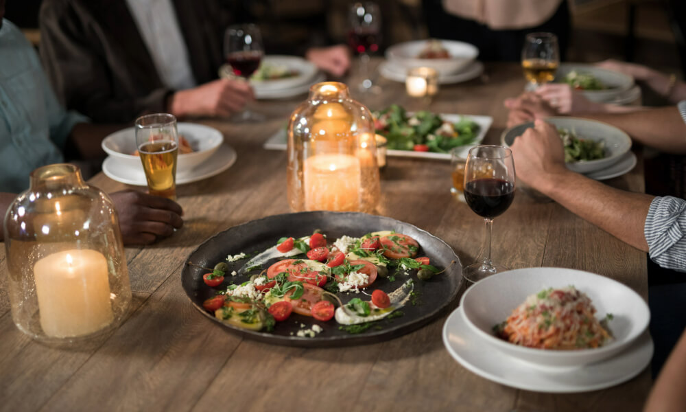 A candlelit table with fresh salads and wine at a local restaurant, reflecting the vibrant dining scene near Arbor Terrace, a senior living community near Greenbelt, MD in Lanham.