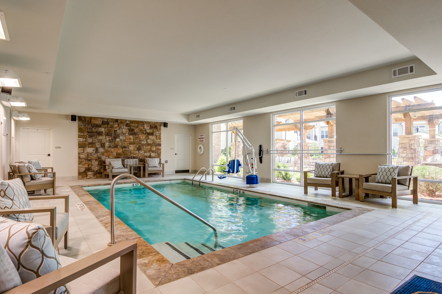 A sparkling indoor pool surrounded by comfortable seating and large windows at Arbor Terrace Hamilton Mill, a senior living community in Dacula, GA, offering a warm and inviting space for relaxation and wellness.