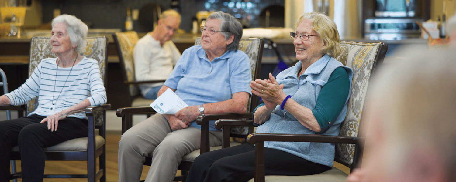 Seniors smile and clap with enthusiasm during a live performance or group event at this senior living community in Dacula, GA, enjoying the vibrant and engaging activities offered.
