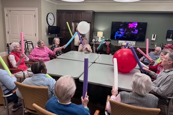 Residents playing a game on the table with a ball and pool noodles 