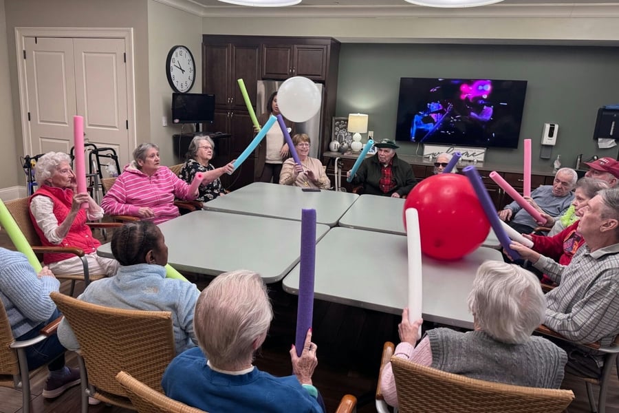 Residents playing a game on the table with a ball and pool noodles 