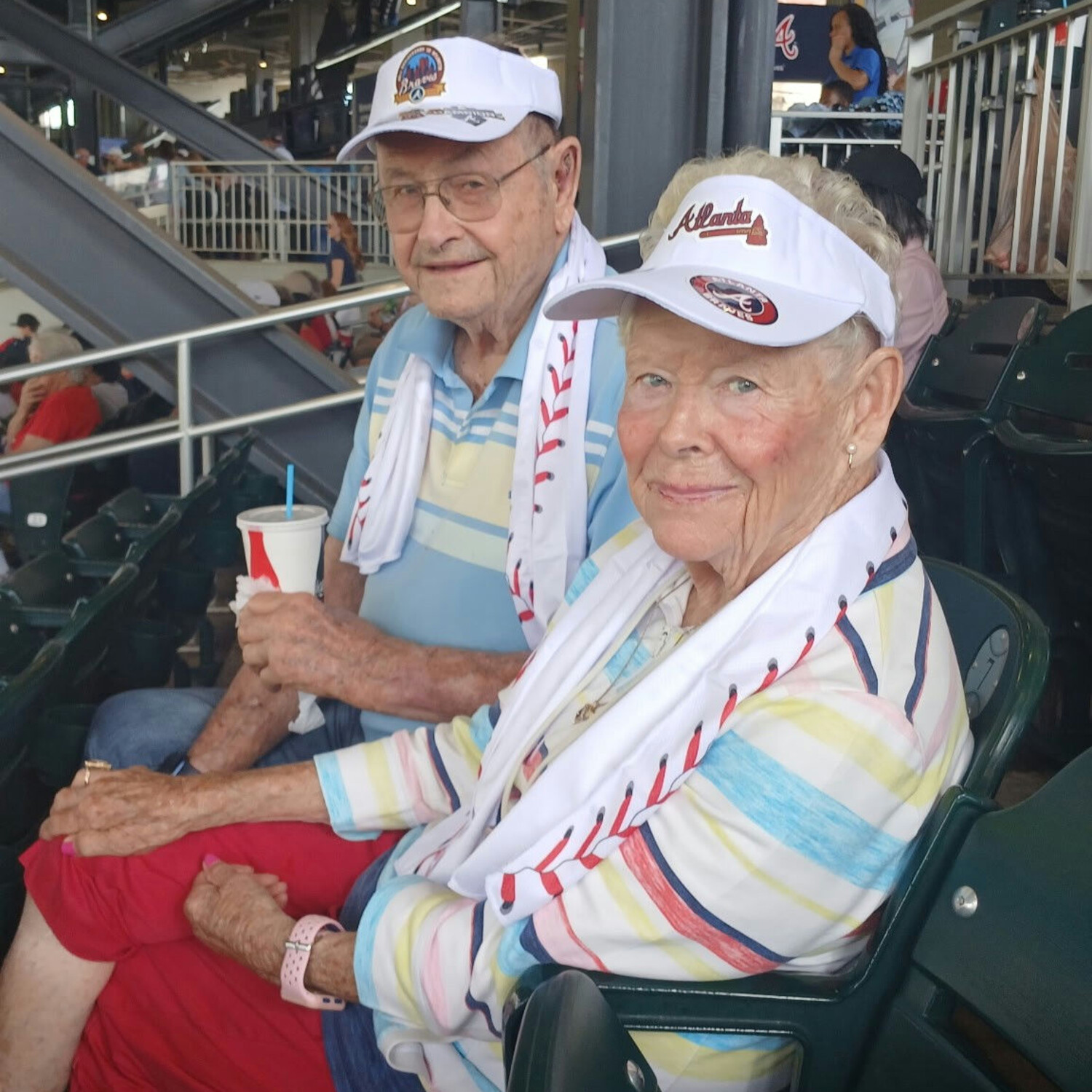 Two seniors enjoying a baseball game together in the stands, smiling and dressed in Atlanta Braves gear — active senior lifestyle Dacula at its finest, with outings and fun at the heart of community life.