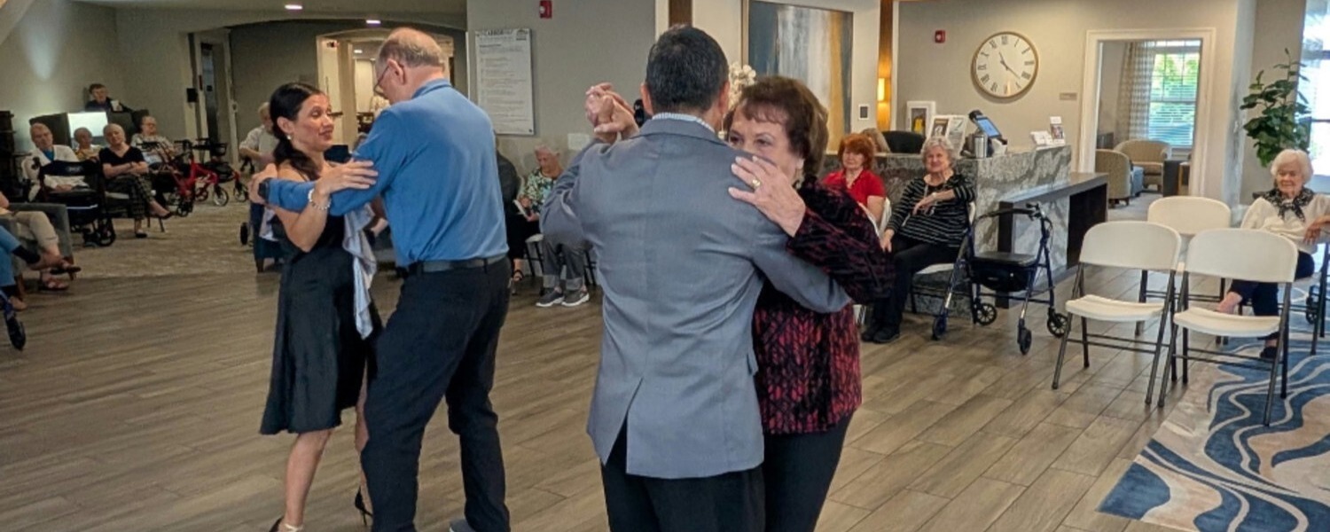 Two couples dance gracefully in a spacious common area while residents look on and enjoy the entertainment, showcasing the vibrant assisted living with activities in Northeast Atlanta.