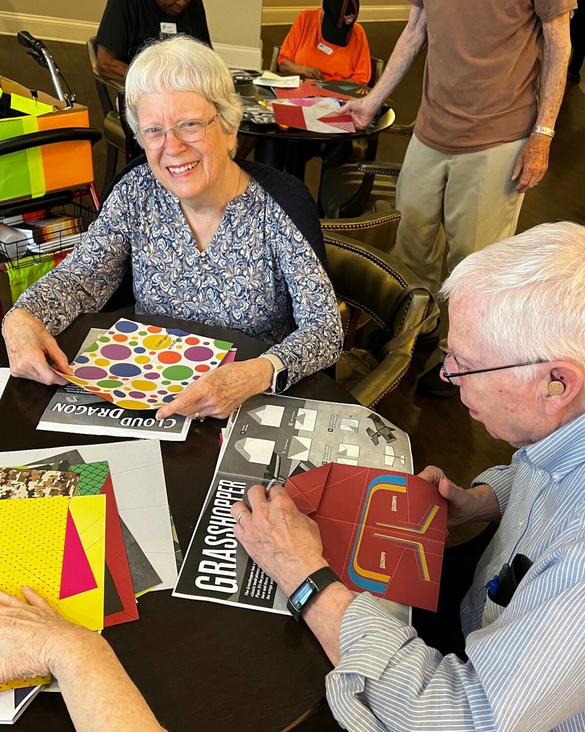 Two seniors share a warm moment during a small-group activity, embodying the connection and engagement at the heart of this dementia care community near Hamilton Mill.