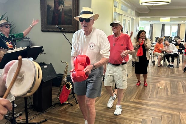 A lively indoor event fills the dining area at Arbor Terrace Hamilton Mill, with people dancing and playing instruments, reflecting the active senior lifestyle and vibrant assisted living community in Dacula, GA.