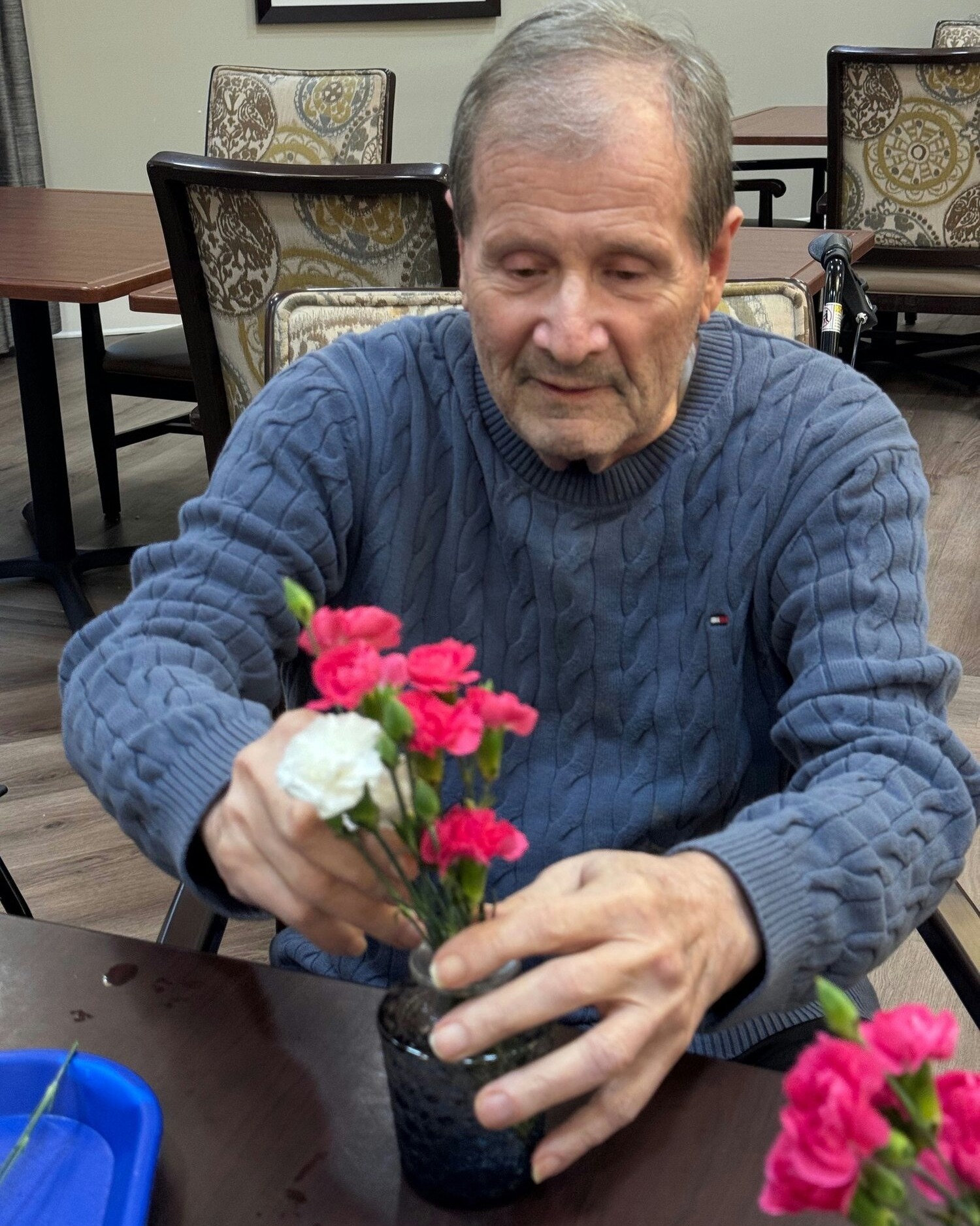 A senior carefully arranges a bouquet of pink and white carnations during a floral activity at this senior living community near Hamilton Mill, GA, enjoying a peaceful and creative afternoon.