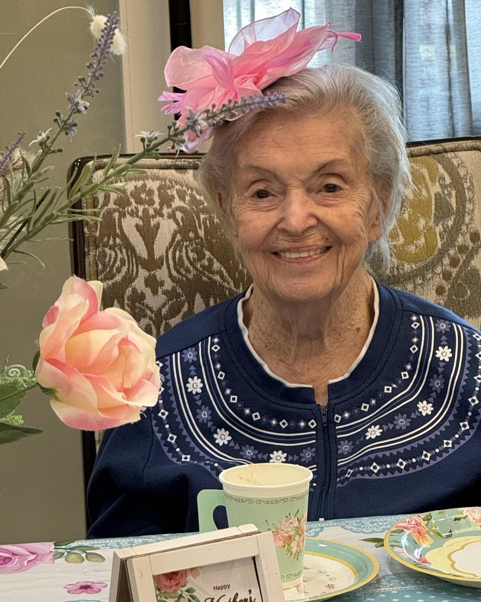 A senior resident smiles warmly while enjoying a quiet morning with tea and flowers, embracing the peaceful daily rhythm of independent living Dacula GA.