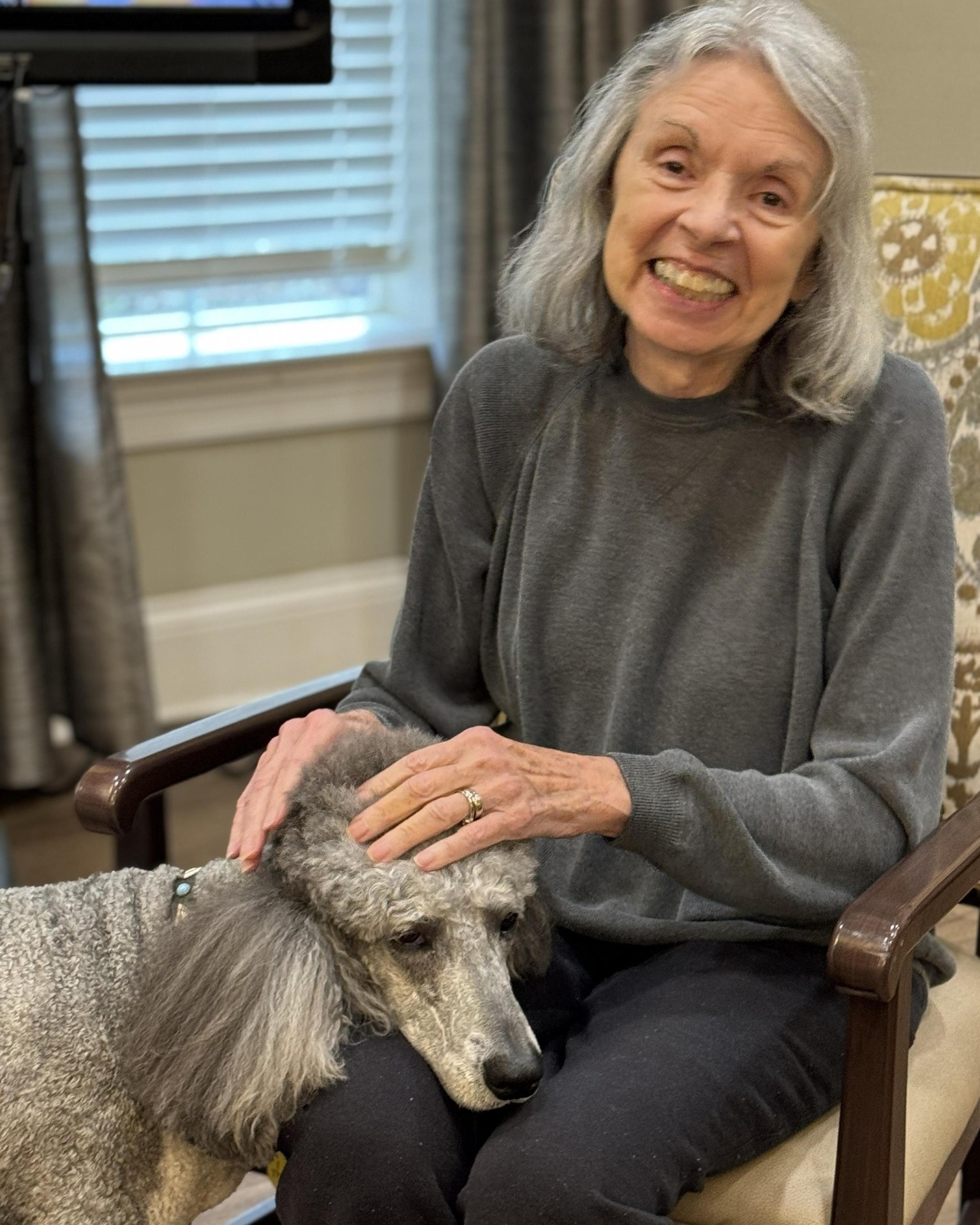 A senior resident relaxes indoors with her small dog, enjoying the comfort and companionship that define the pet-friendly senior living experience near Hamilton Mill.
