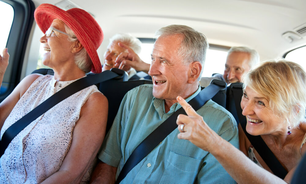 A group of seniors laughing and chatting together on a shared outing in a vehicle — the kind of active senior lifestyle Dacula GA residents enjoy at Arbor Terrace Hamilton Mill.